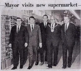 Historical newspaper clipping with headline 'mayor visits new supermarket' and image of mayor with suited colleagues