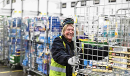 Smiling colleague pushing a trolley of stock.