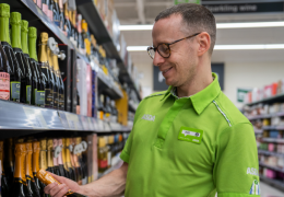 Happy colleague picking out a bottle of wine.